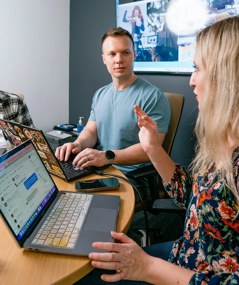 Dos personas conversando en una reunión con laptops
